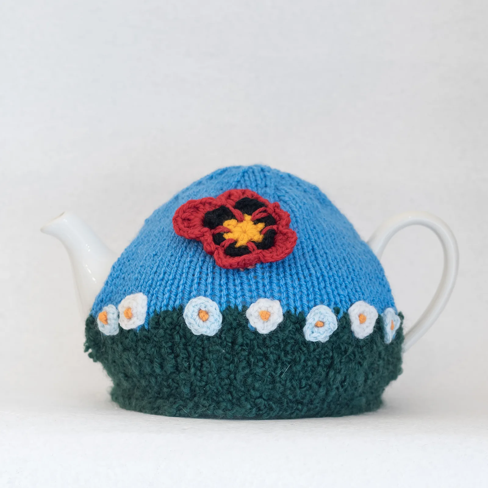 hand knitted tea cosy with flowers blue green
